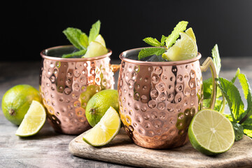 Moscow mule cocktail served with ice and lime slice on wooden table.