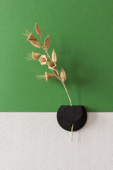 Wall vase for dried flowers. Flowers made from straw on a green  background. Straw wall decoration.