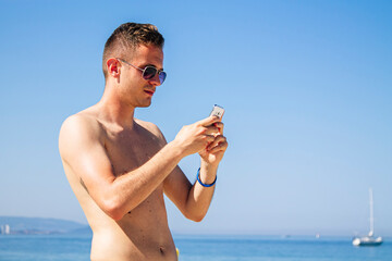 young man using his mobile phone on the beach