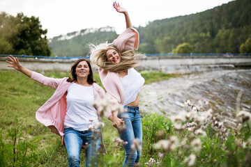 Adult daughter spending time with her mother, having fun, laughing. Mom and daughter outdoors, on...
