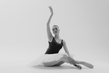 Young ballerina in elegance tutu and pointe shoes dancing against white background.