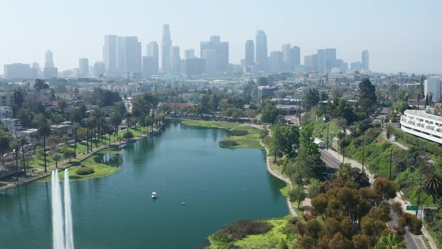 Aerial pullback shot of Echo Park lake, fountains, trees, LA offices buildings