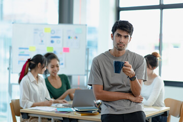 Asia young creative people in smart casual wear looking at camera in office workplace.