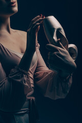 Closeup view to young ballerina holding pointe shoes in her hands.