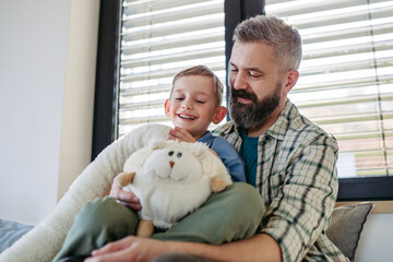 Portrait of smiling boy with father, holding his favourite plush toy.