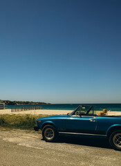 a blue convertible near the beach