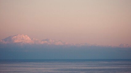 Fluffy clouds sunset sky above calm sea with space for text. Miminal coastal banner.