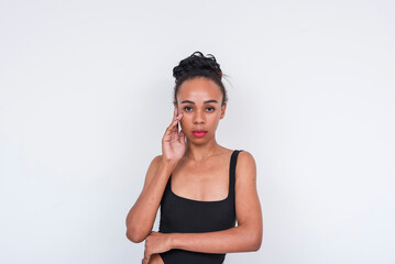 Confident mixed-race woman in black bodysuit standing against a white background