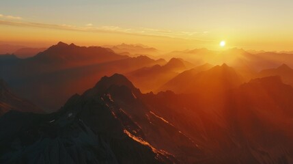 Naklejka premium A panorama of a breathtaking sunset over a vast mountain range, showcasing the dramatic peaks bathed in warm light