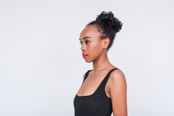 Confident mixed race woman in a black bodysuit posing on a white background