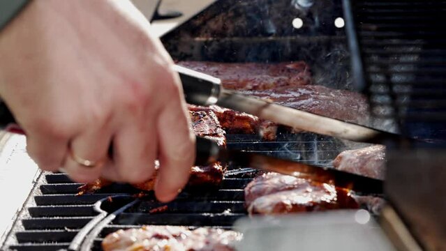 Watch the video of grilling steaks on a gas grill for a delicious cooking experience. Ribeye or pork steaks are prepared with tongs, showcasing the art of grilling cuisine