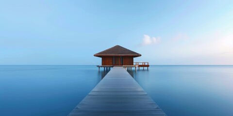 A peaceful overwater bungalow extends over a calm blue ocean, offering a serene getaway with a clear sky.