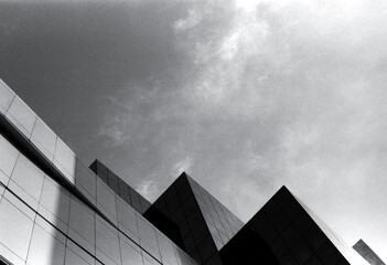 blurred and defocused walls and corners of large buildings under the cloudy sky in black and white tone, captured with a film camera.