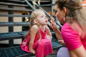 Deaf child with cochlear implant for hearing audio and aid for impairment having fun and laughs with mother outdoor in summer. Sound fitting device to help with communication listening and interaction