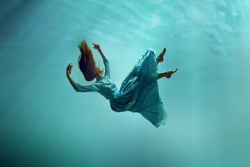 Music album cover. Mysterious elegant young girl in ender dress levitating underwater with sunlight...
