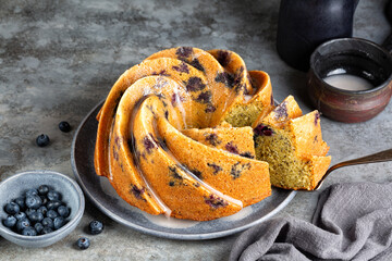 Orange Blueberry Bundt Cake with poppy seed and icing. Homemade bakery. Dark grey background.