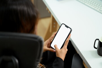 Close up businesswoman holding smartphone with blank screen sitting at her workplace