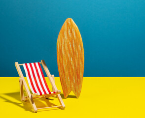 Beach chair and surf board on blue and yellow background.