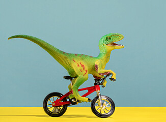 Cute happy green dinosaur riding bike on blue and yellow background.