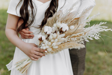 A bride and groom are posing for a picture with a bouquet of white flowers