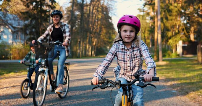 happy young girl cycling together with family. bike ride