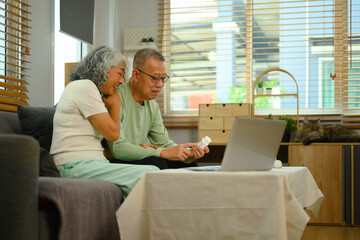 Elderly couple sitting in the living room and talking to their doctor via video call. Telehealth concept