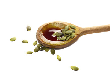 Pumpkin oil puddle in wooden spoon and pile seeds isolated on white, side view