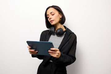 Fototapeta premium Stylish young woman in a fashionable look reads a book on a tablet on a white background with copy space