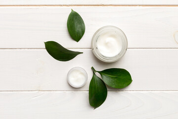 Organic cosmetic products with green leaves on wooden background. Flat lay