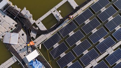 Professional workers clean and inspect solar panels on a floating buoy. Power plant with water