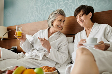 A tender senior lesbian couple enjoying a peaceful moment while seated on a comfortable bed.