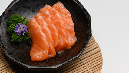 Delicious sashimi salmon arranged on a black stone plate with parsley leave