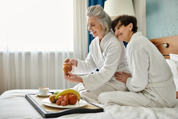 Senior lesbian couple enjoying a peaceful moment sitting on a bed together.