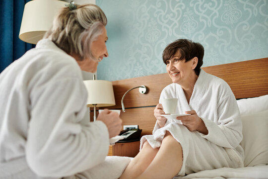 A senior lesbian couple sitting on a bed, engrossed in deep conversation. - Powered by Adobe