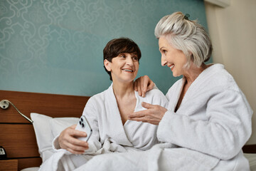 Senior lesbian couple share a tender moment on a bed.