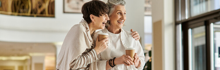 Senior lesbian couple stand together, showing love and tenderness.
