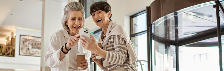 A senior lesbian couple standing together in a hotel, radiating love and tenderness.