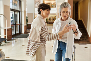 Senior lesbian couple share a moment while looking at a cell phone.