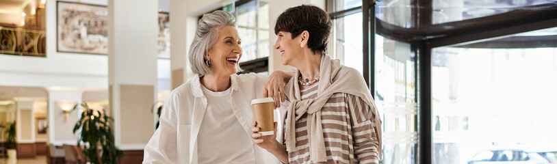 A tender moment between a loving senior lesbian couple, standing together in a hotel.