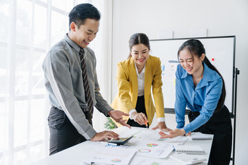 Fototapeta premium Collaborative Strategy: Three Asian business professionals collaborate on a project, their smiles and engaged postures radiating a positive and productive work environment. 