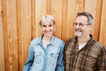 Happy Middle-Aged Couple Laughing Together in Front of Wooden Wall