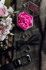 A man's outfit is adorned with a pink flower, a tie, and a bow. The outfit is elegant and...