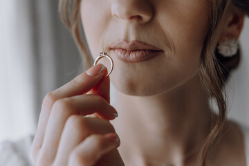 A woman is holding a ring in her mouth. The ring is gold and has a diamond in the center. The...