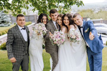 A group of people posing for a picture, including a bride and groom. The bride is holding a bouquet...