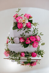 A three tier cake with pink flowers and a white and pink orchid on top