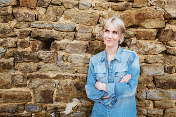 Thoughtful Woman in Denim Shirt Leaning Against Stone Wall