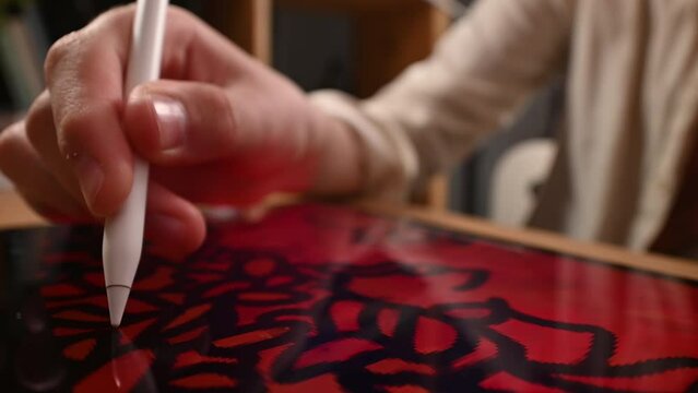 A teenager carefully draws lines on a tablet pad using an electronic pen and zoom and pan gestures with his second hand.