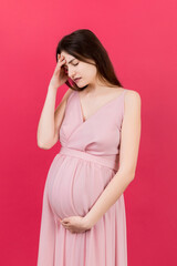 Beautiful young pregnant woman feeling head ache on colored background isolated. Stressed pregnant woman or mother problems