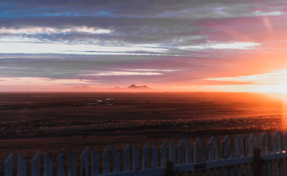 A beautiful sunset over a desert landscape with a fence in the foreground