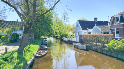 Boats leisurely glide through the calm canal lined with charming houses on a tranquil day